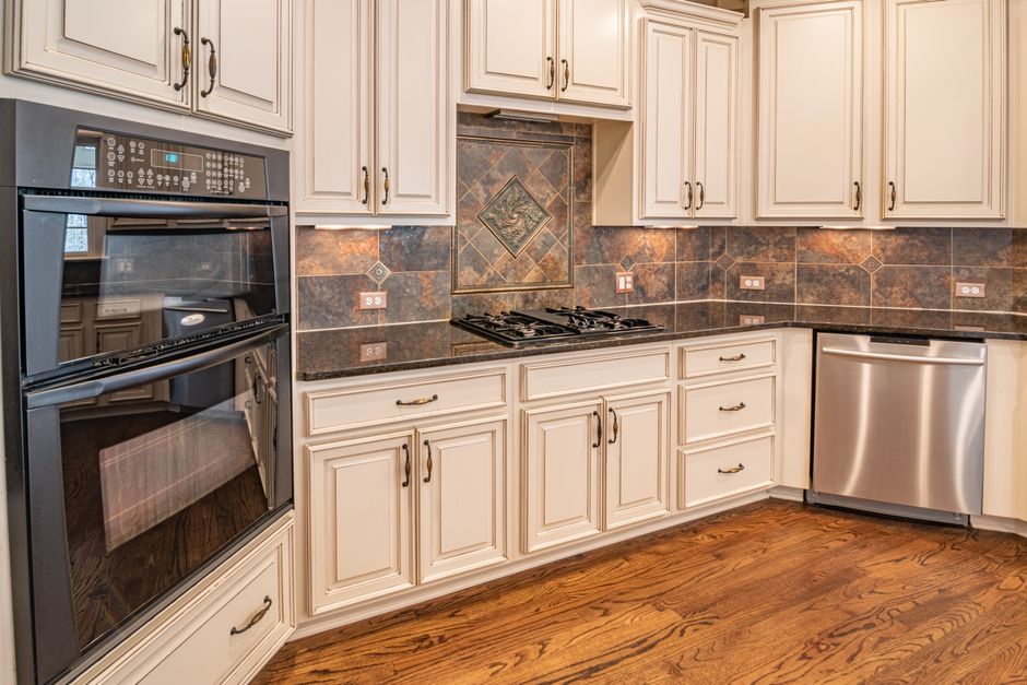 A modern kitchen featuring cabinets, a dishwasher, and a double oven with hardwood floors